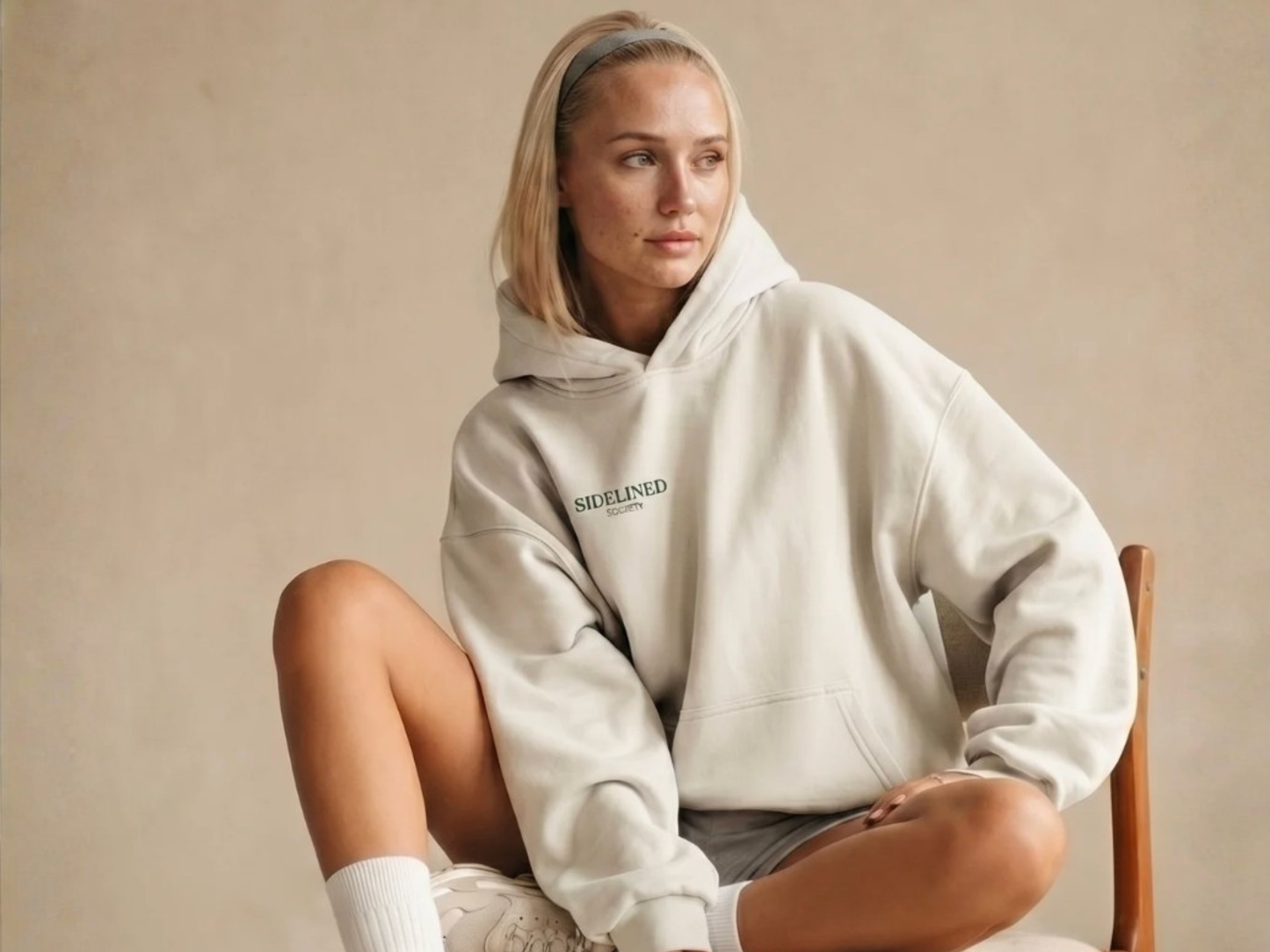 Woman wearing oversized cream Sidelined Society hoodie with relaxed fit